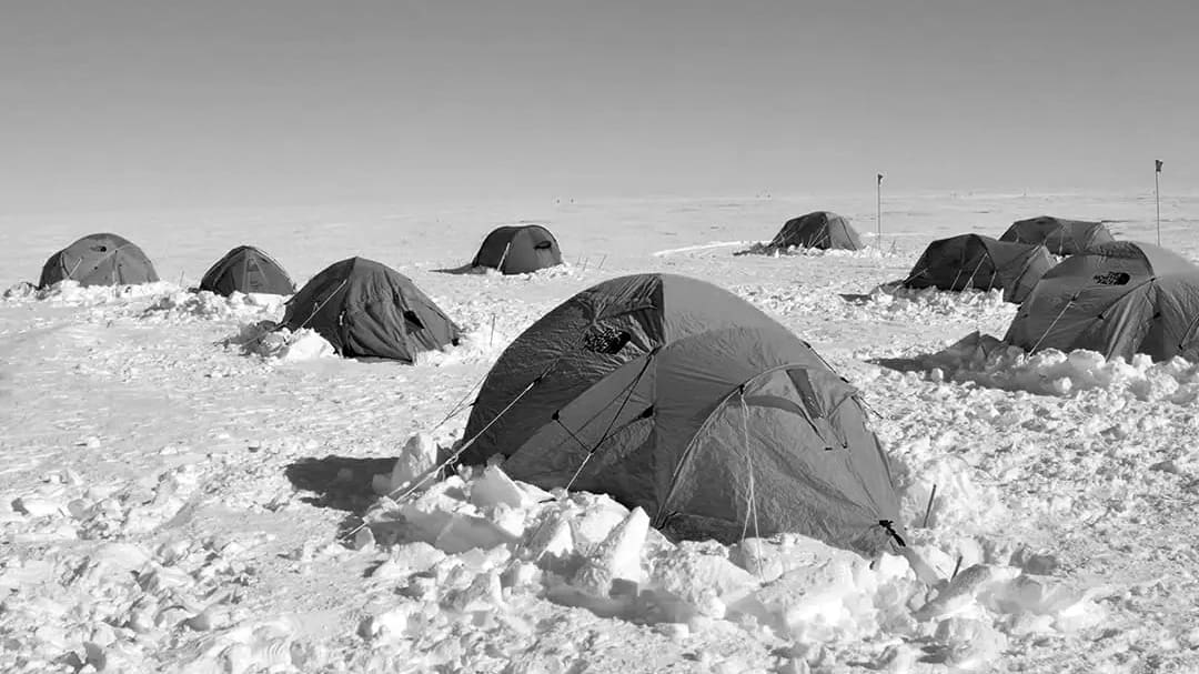 Tents on snowy landscape under clear sky.