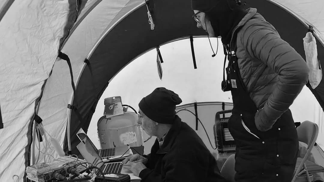 Two scientists working in a research tent.