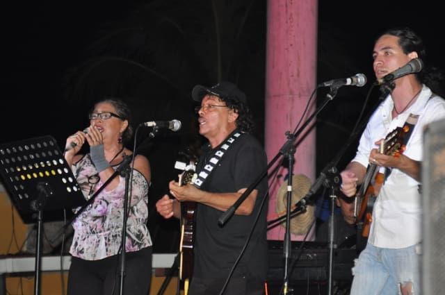 Three musicians performing on stage with microphones.