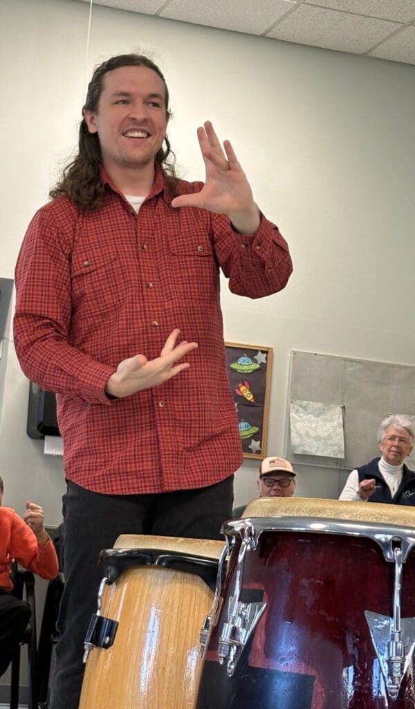 Man gesturing while leading a conga drum class