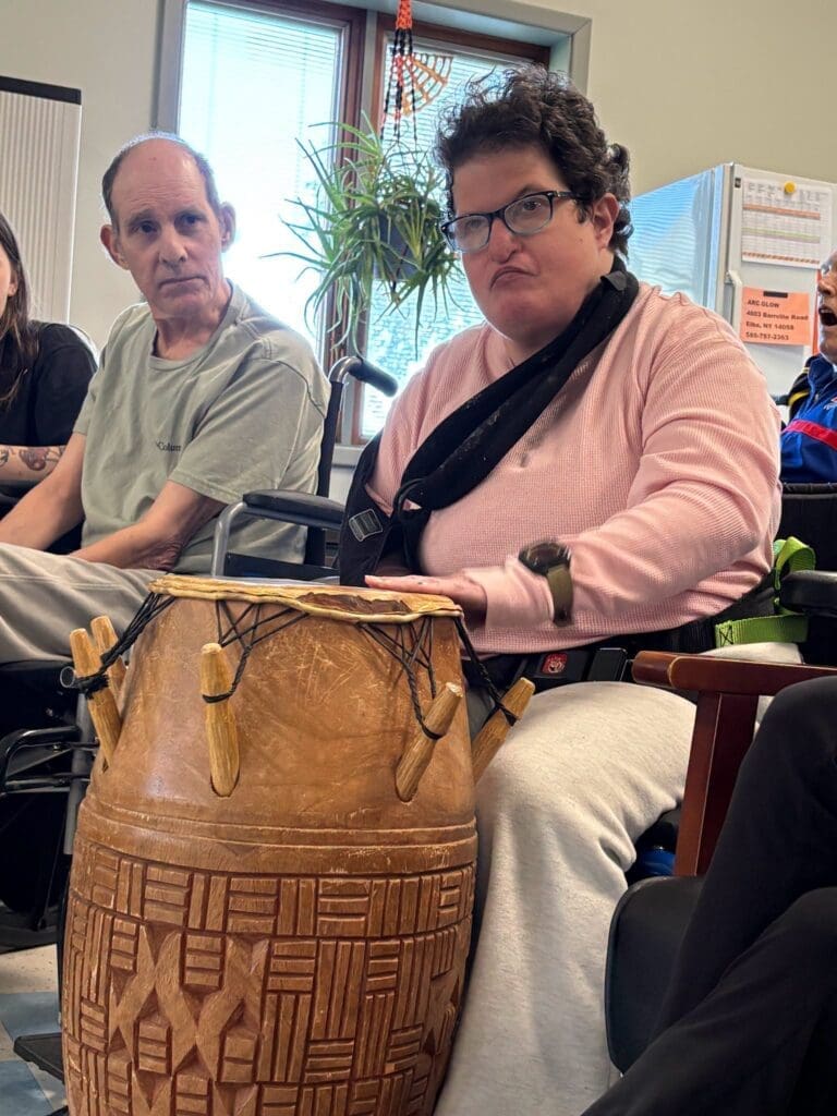 Woman playing wooden djembe drum indoors near man